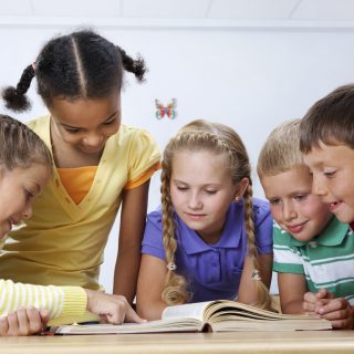 Five young children reading a book together