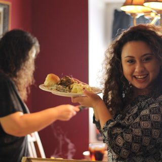 Two Women getting Plates of Food for a Family Dinner