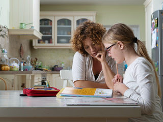 Parent and child at kitchen table doing homework