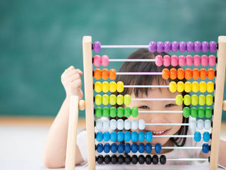 smiling child hides face behind colorful abacus