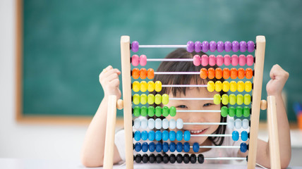 smiling child hides face behind colorful abacus