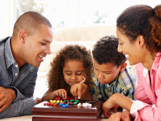 Two parents and tow children playing a board game