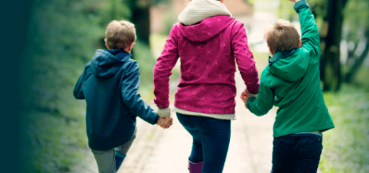 two children and parent walk down sidewalk