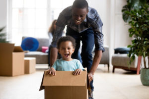 father pushing smiling child in cardboard box