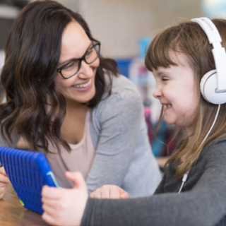 teacher with child wearing headphones and using a tablet