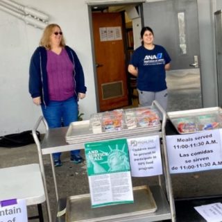 four school staff distributing meals standing 6 feet apart