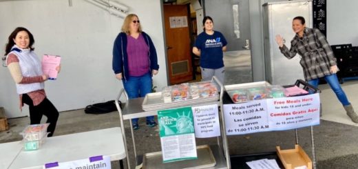 four school staff distributing meals standing 6 feet apart