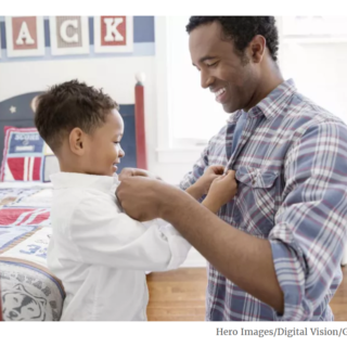 Dad and young son in his bedroom buttoning each other's shirts