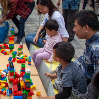 adults appearing to be of asian descent playing with blocks with young children at a table