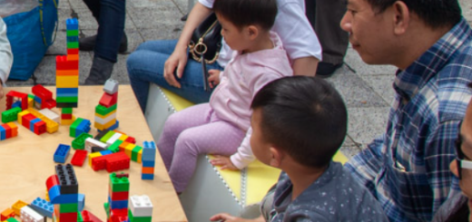 adults appearing to be of asian descent playing with blocks with young children at a table