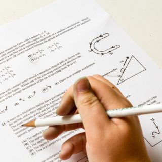 Photo of hand holding a pencil in front of a math test