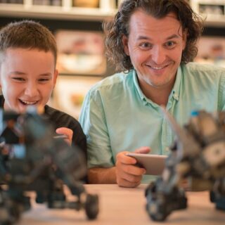 Father and son each playing with a small robot