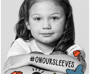 Black and white photo of young girl with #ONOURSLEEVES on her arm