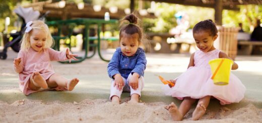 Three toddlers playing in the sand together