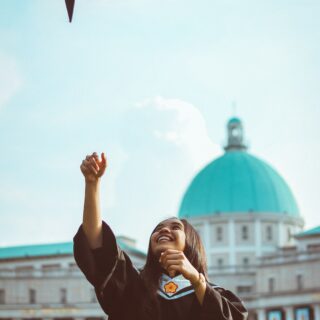 Female student graduate tossing her mortar in the air