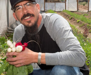 A person in a garden holding fresh radishes