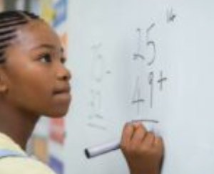 Elementary school girl writing math equations on a whiteboard
