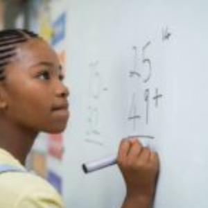 Elementary school girl writing math equations on a whiteboard