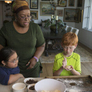 An adult helping two children bake